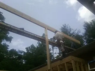 Carpenter setting a ridge beam over a new addition frame — Ice Dam Removal by Roofing Brothers in Eidson