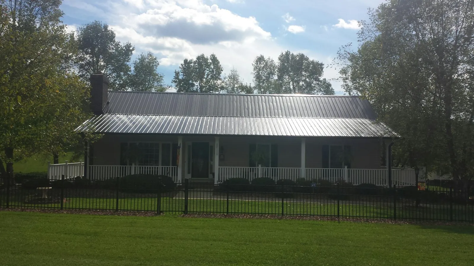 Gray metal roof on a brick ranch with a full width front porch — Gutter Guard Installation work by our crew in Eidson