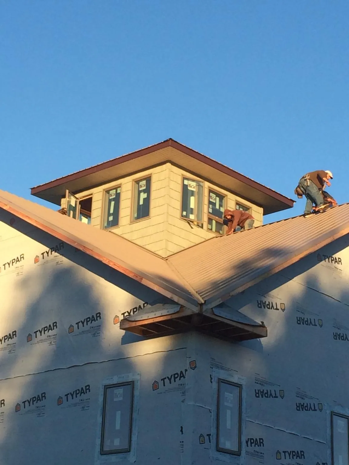 Roofers working around a rooftop cupola on a new metal roof at sunset — Roof Waterproofing in Eidson by Roofing Brothers